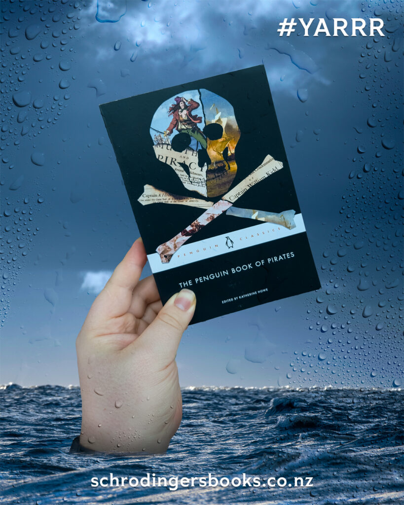 a hand emerging from the sea holding a copy of "The Penguin Book of Pirates"